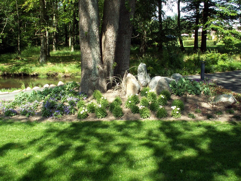 Forhøjet bed med beplantning og pyntesten i granit